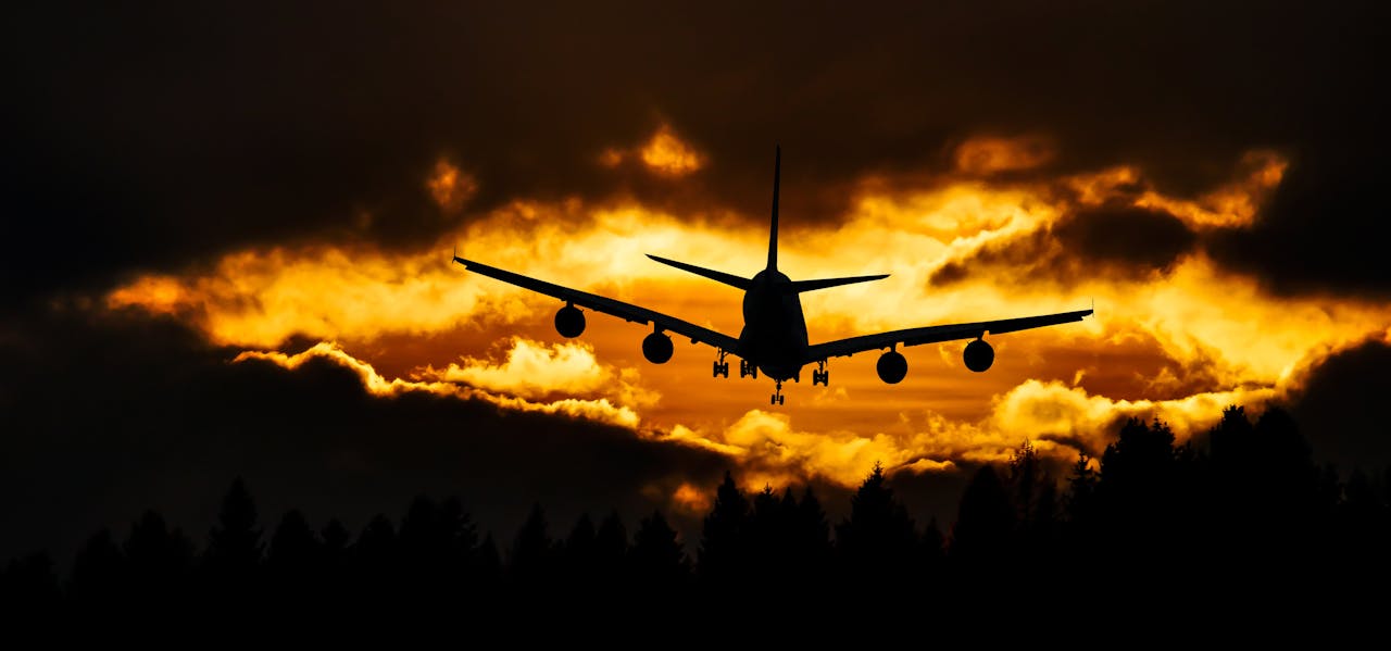 Airplane silhouette glides through a dramatic sunset sky, creating a striking aviation scene.